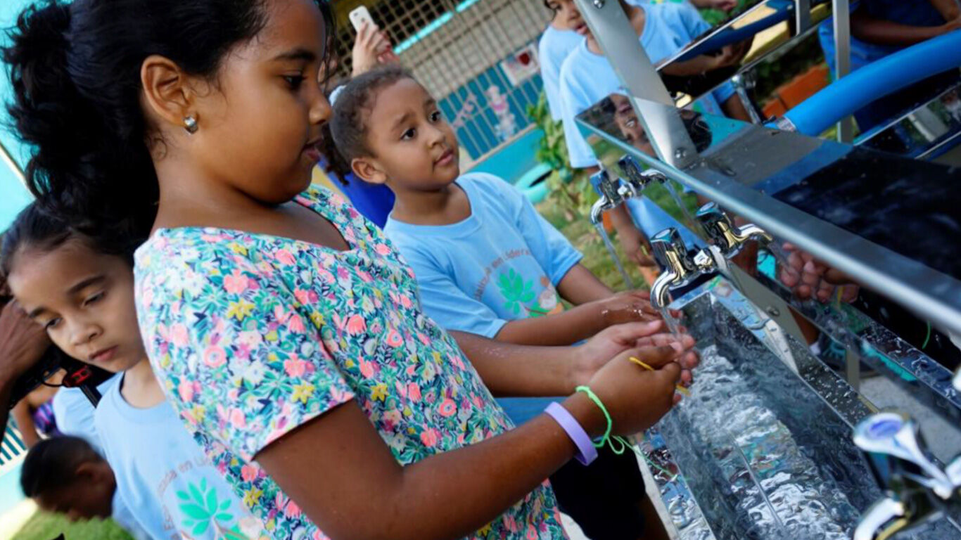 Children washing their hands in an outdoor sink.